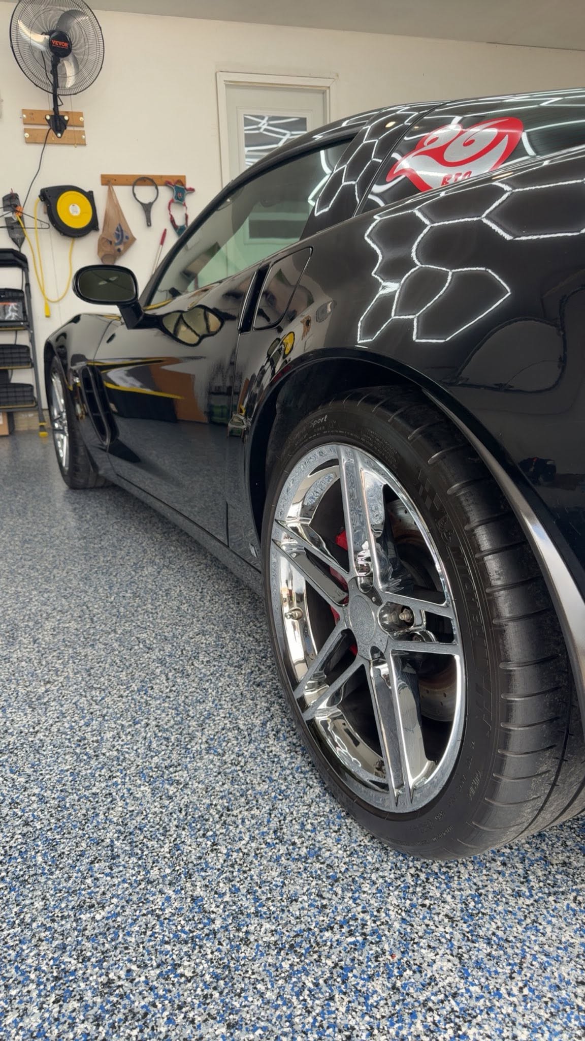 Chrome wheel and red brake caliper on a black Corvette